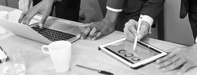 Group of people strategising around a laptop and tablet