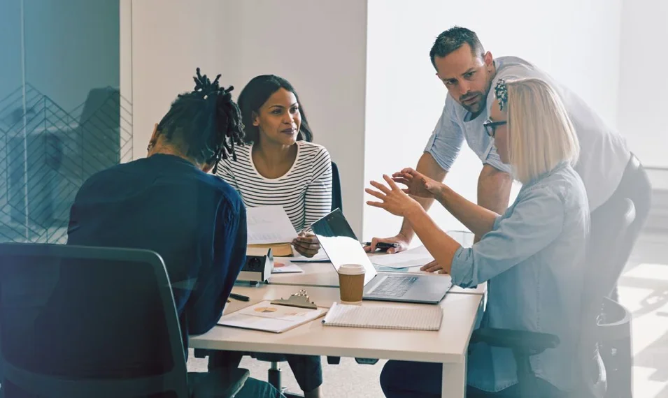 C-Suite members sat around a table speaking and solving problems together